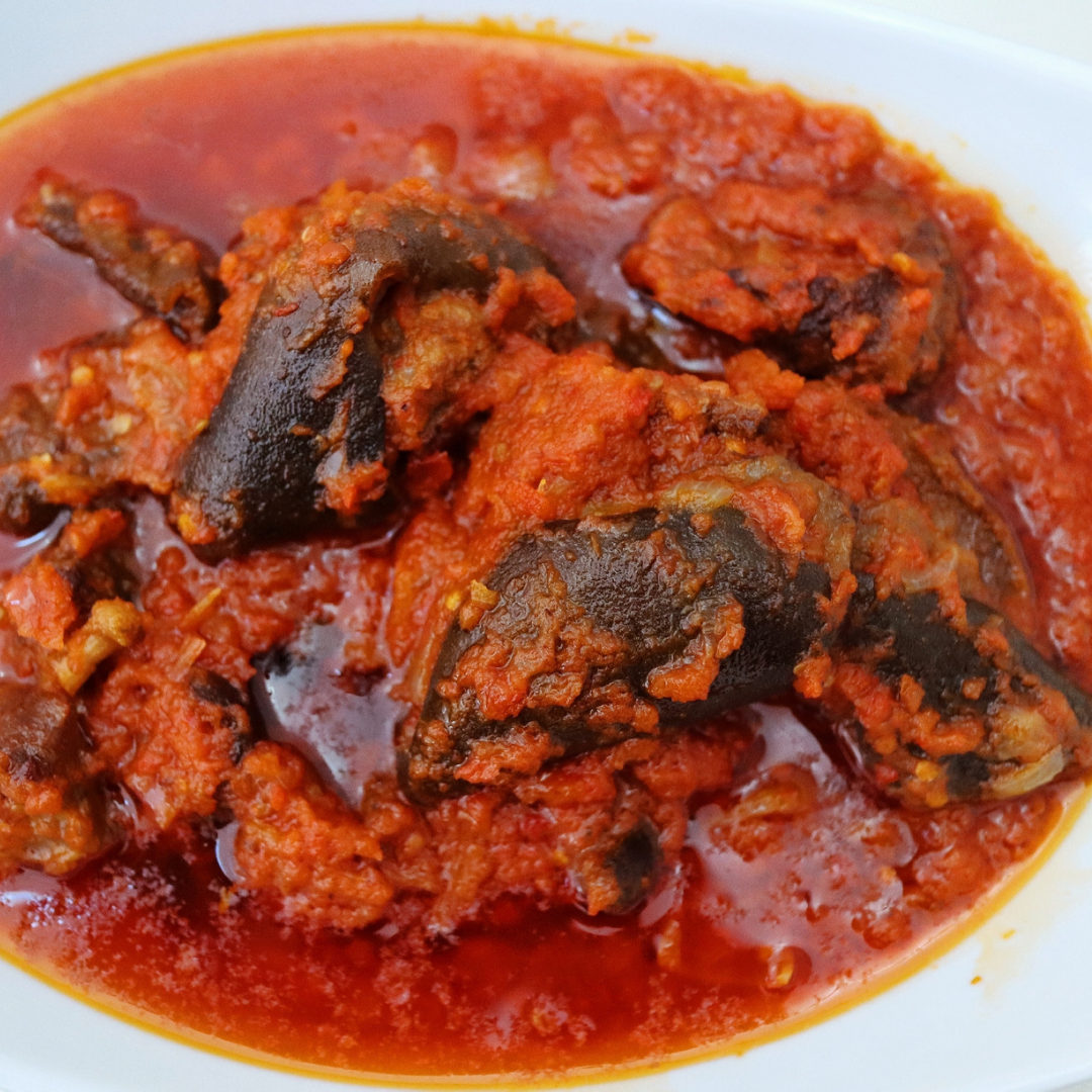 goat meat covered in red sauce in a white bowl